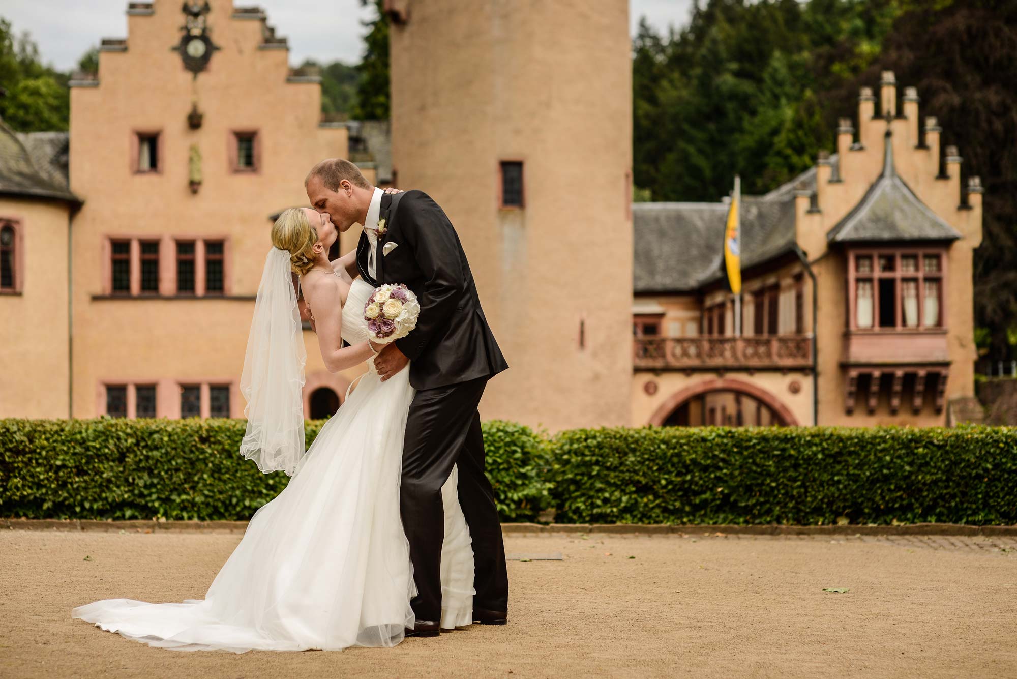 Kuss des Brautpaars vor einem Schloss
